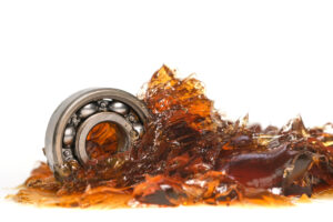 Closed up macro, ball bearing put into yellow transparent lithium grease isolated on white background with copy space, engineering and industrial concept